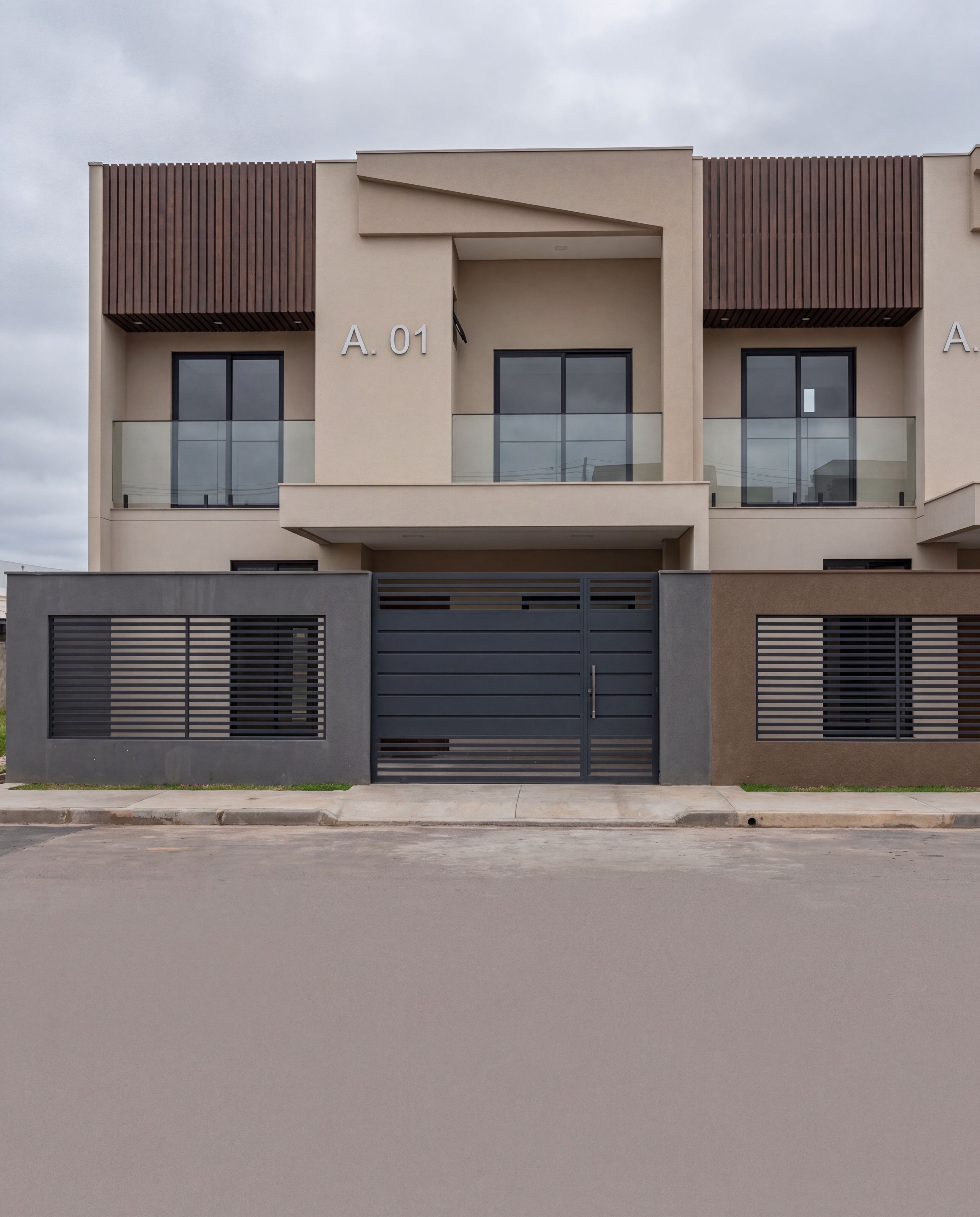 Vista frontal da unidade A.01 com fachada em tons quentes, painel de cumaru superior, sacada com guarda-corpo de vidro e portões ripados horizontais